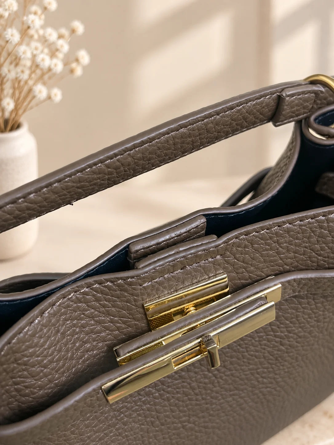Pormenor do fecho dourado da bolsa Éclat taupe
