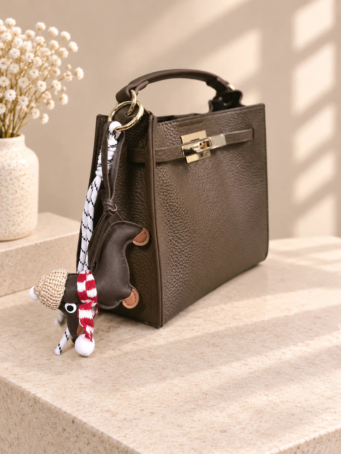 Vista lateral da bolsa Éclat verde azeitona com charm decorativo