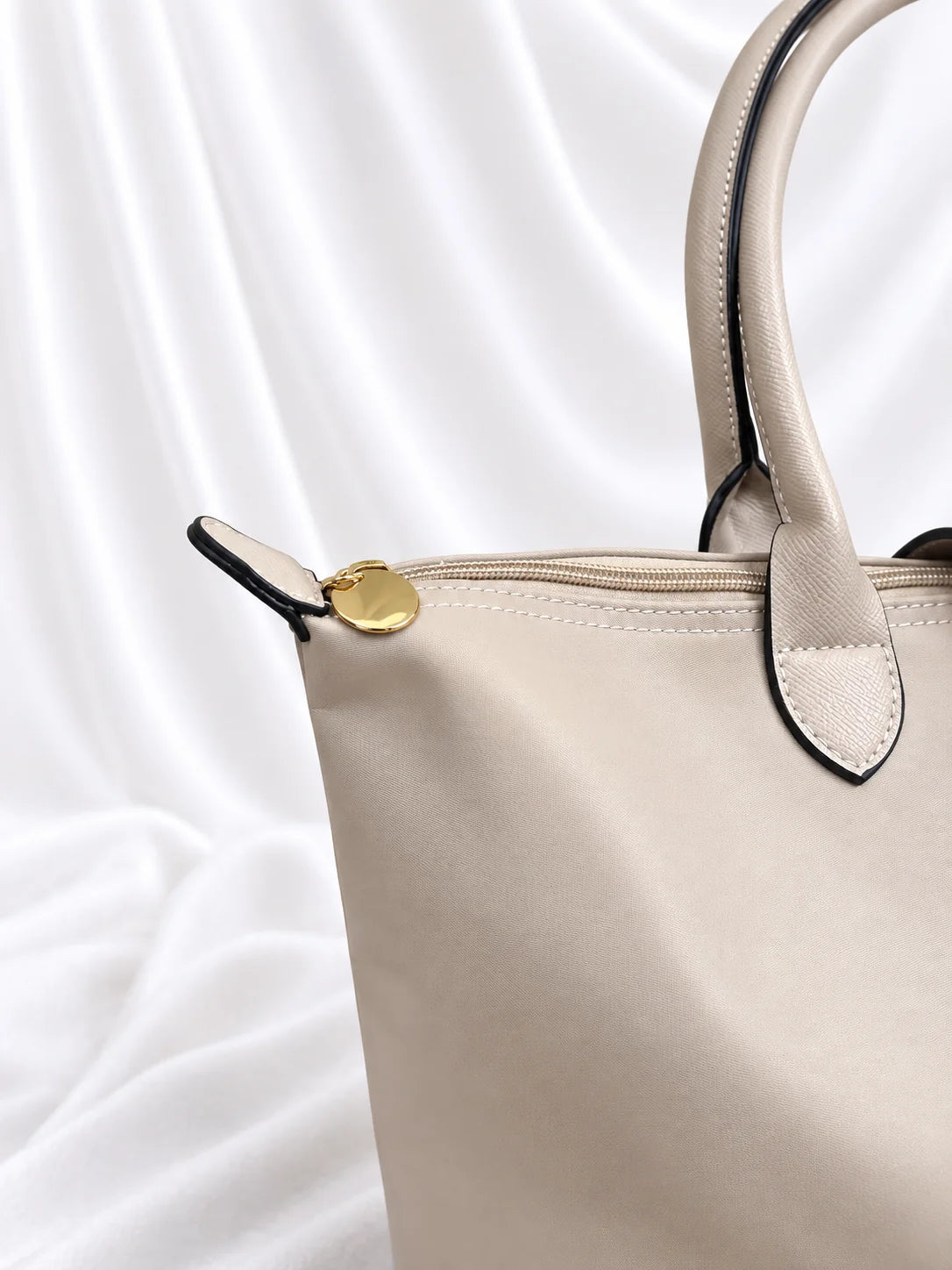 Pormenor do fecho de correr dourado da bolsa Grace bege